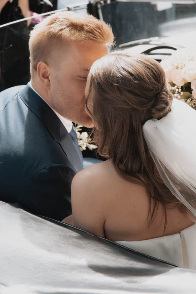 Nydelig bryllupsbikeffekt med par som kysser ved sjøen under bryllup på Hvaler.