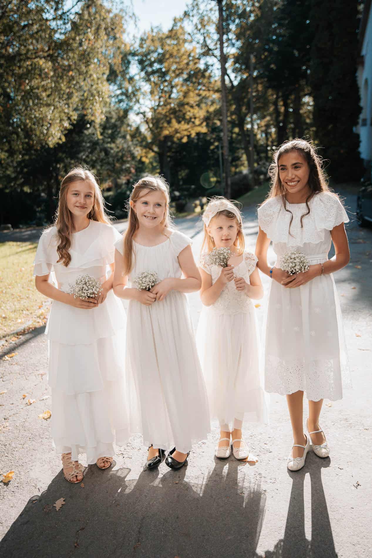 Bryllupsfotograf i Oslo - portrett av fire jenter i hvite kjoler med blomster, solskinn og høstfarge.