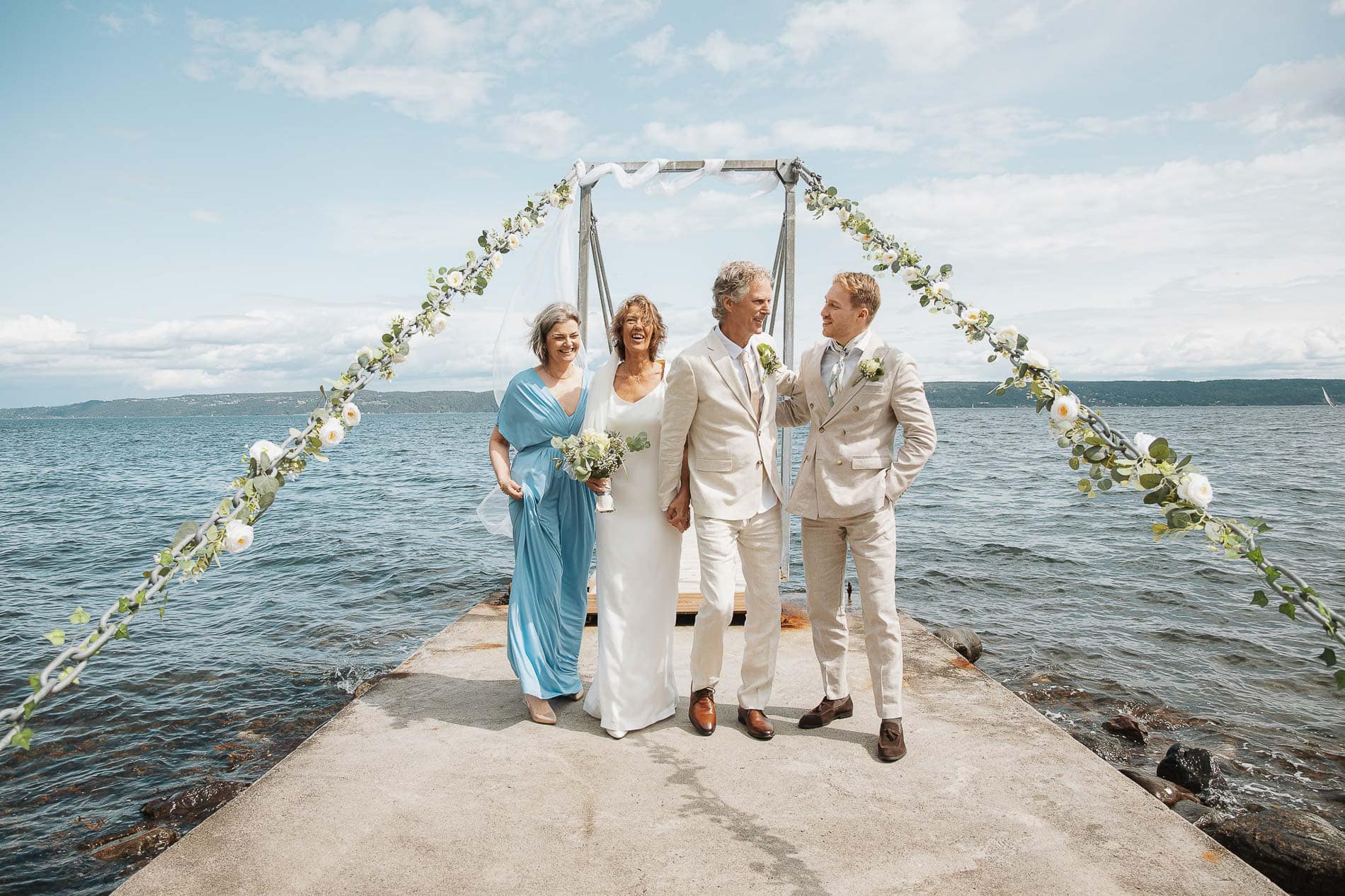 Bryllupsfoto av brudepar og familie på bryllupsseremoni ved sjøen, fotograf Heidi Henriksen.