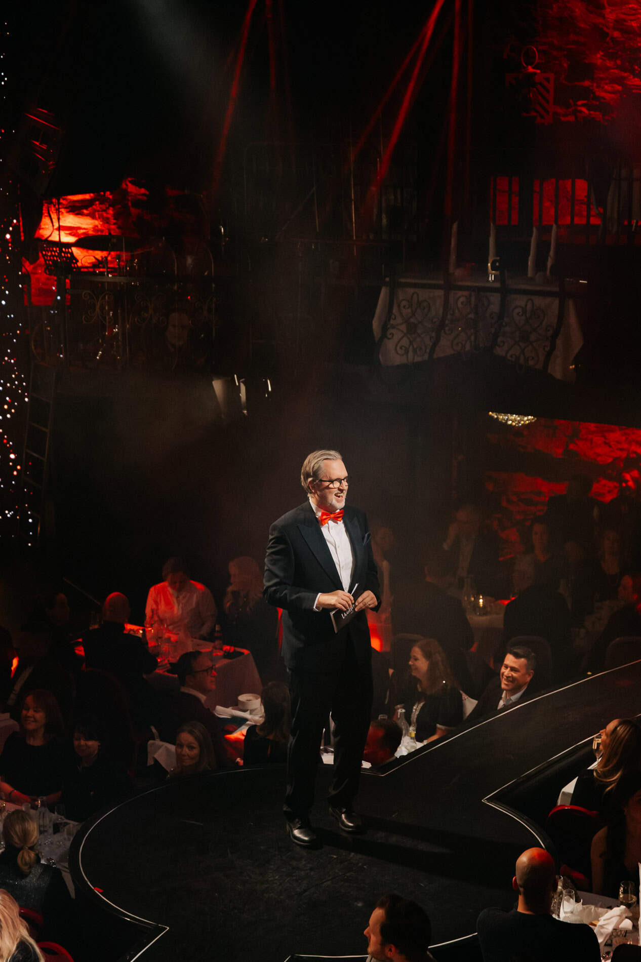 Elegant mann i smoking på scenen under bedriftsarrangement.