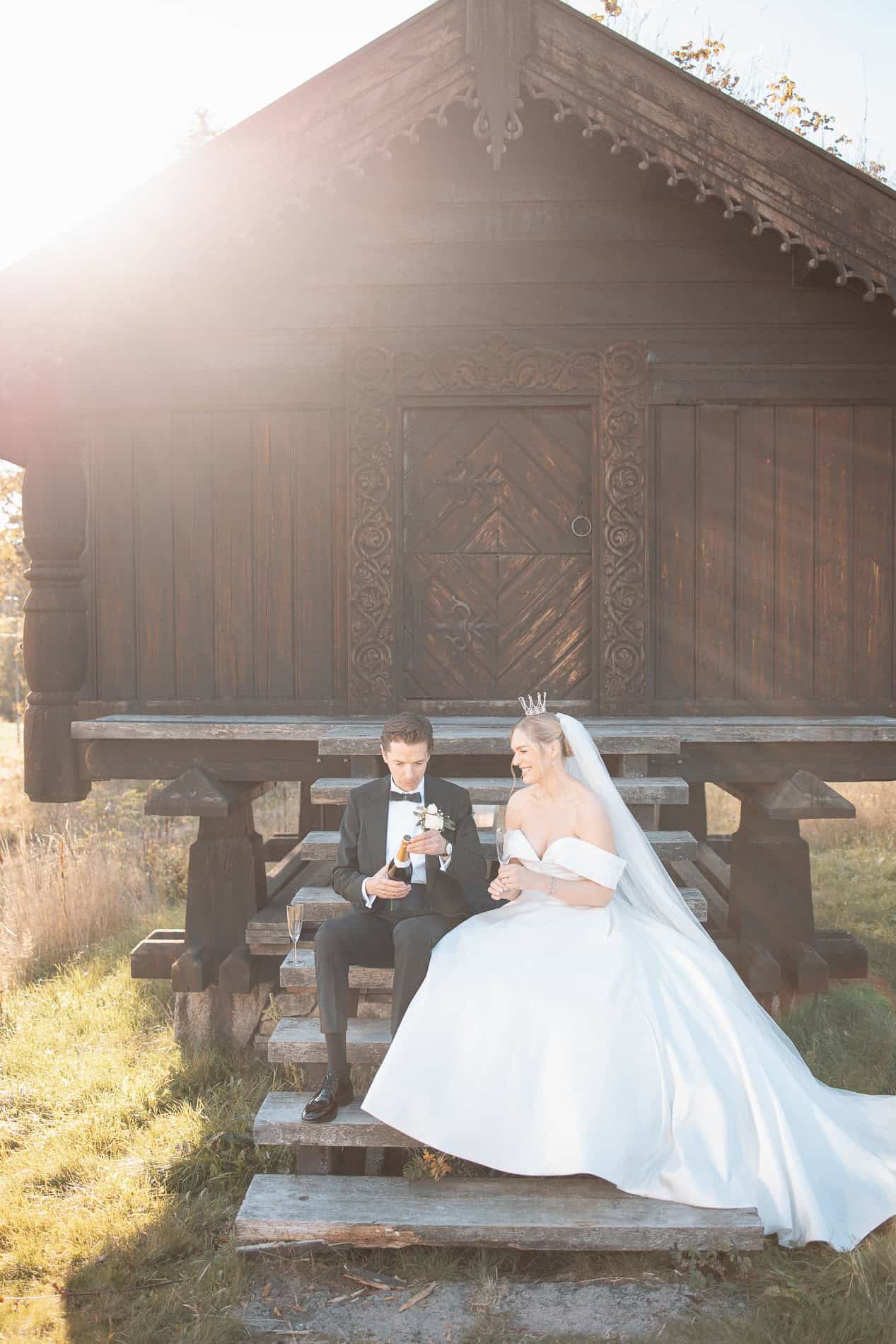 Bryllupsfoto av brudepar foran tradisjonelt trehus i Oslo, solskinn og høstfarger.