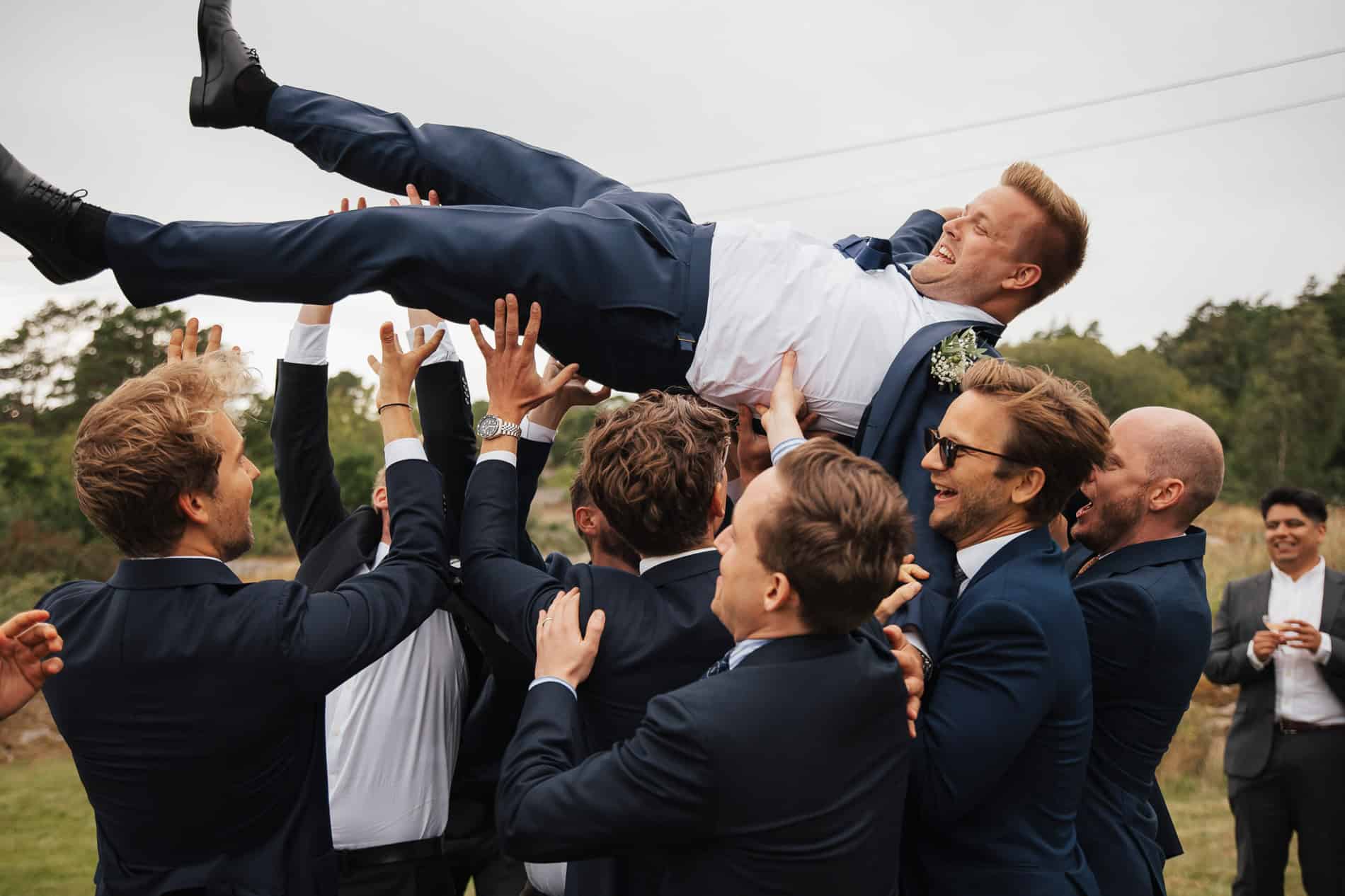 Brudepar løftes av venner under bryllup i Oslo, fotograf Heidi Henriksen.