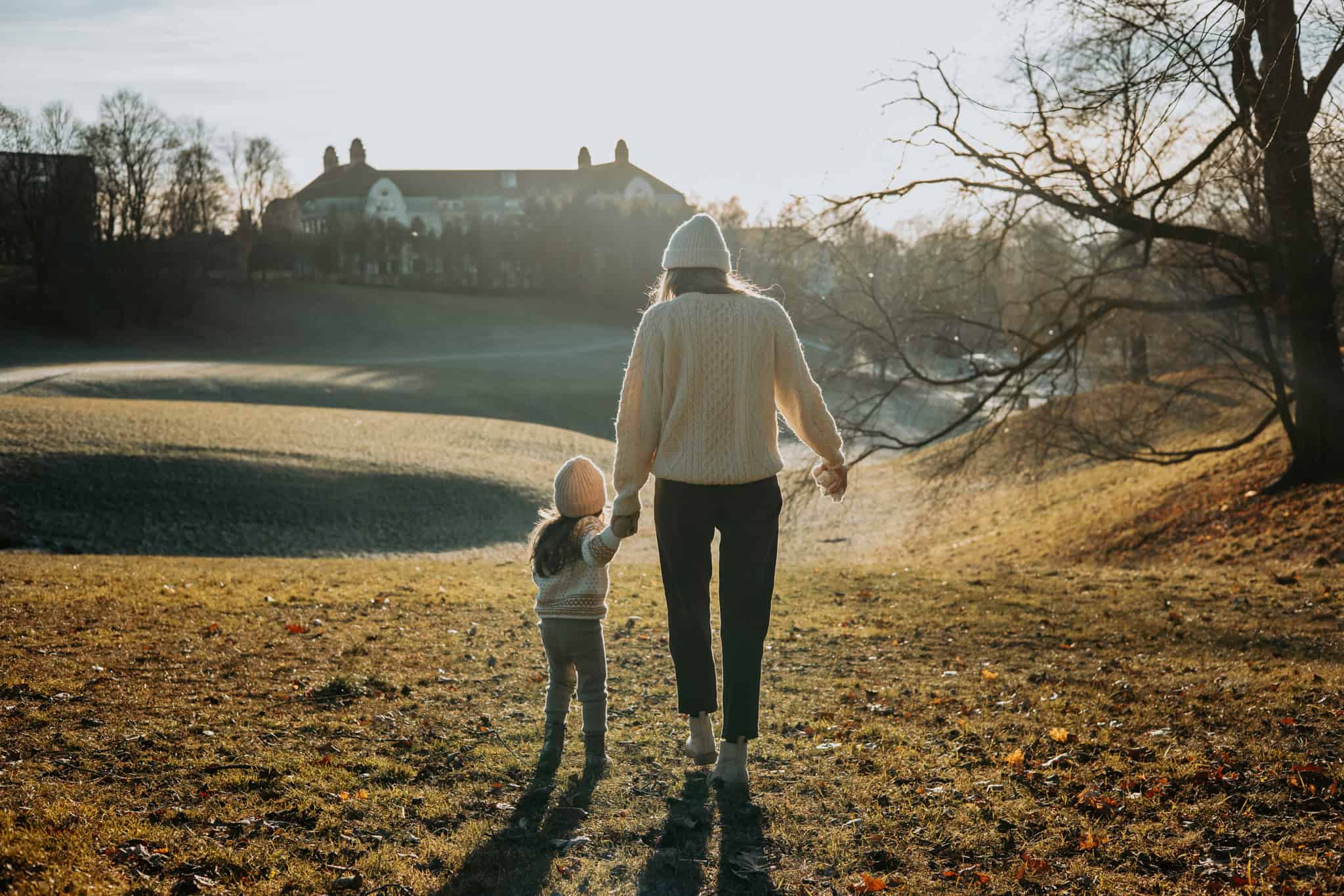 Familie som går hånd i hånd i en park i Oslo, høstlig landskap, solnedgang.