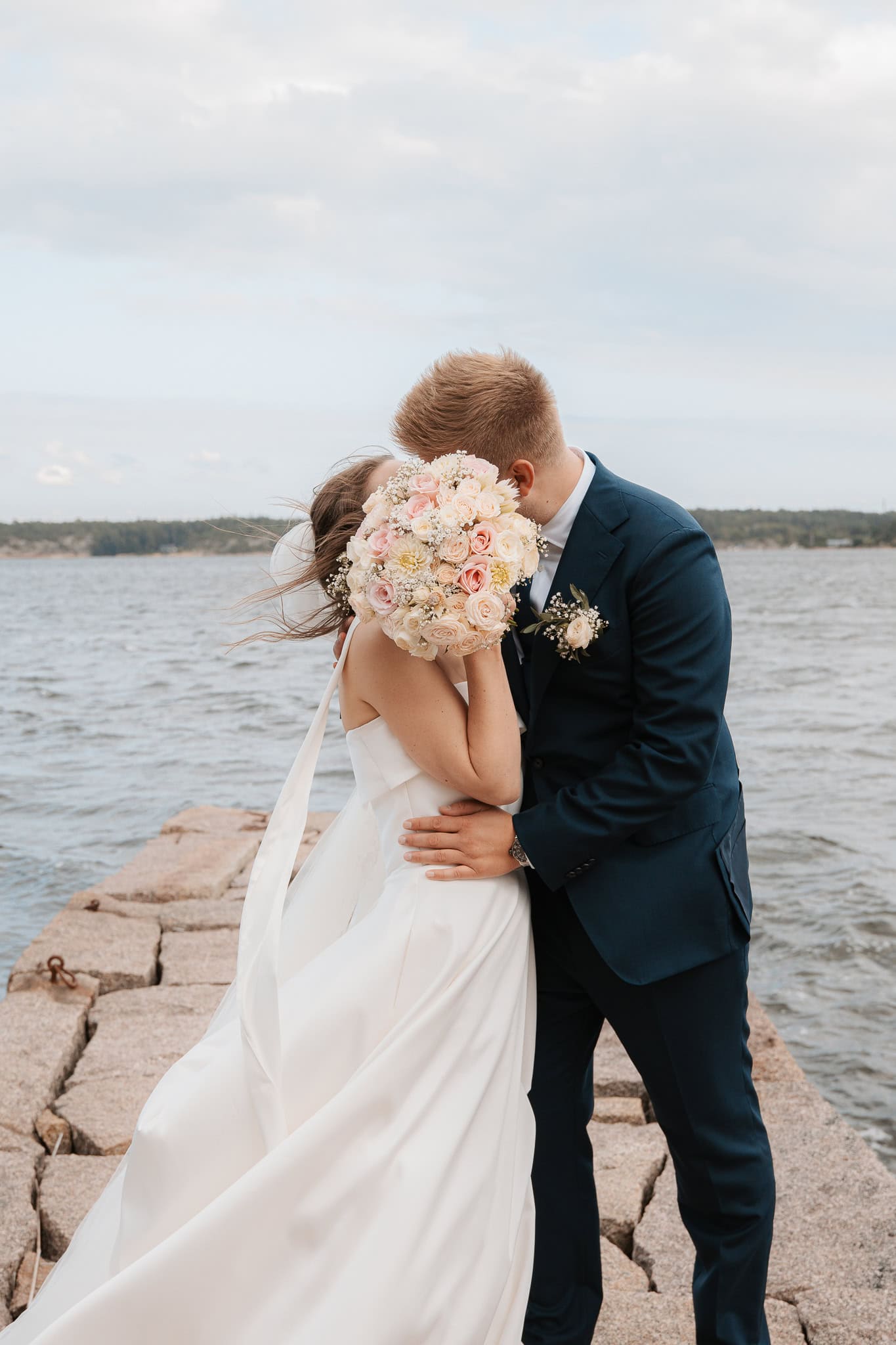 Bryllupsfoto av et par ved vannet i Oslo, med romantisk klem og vakker utsikt.