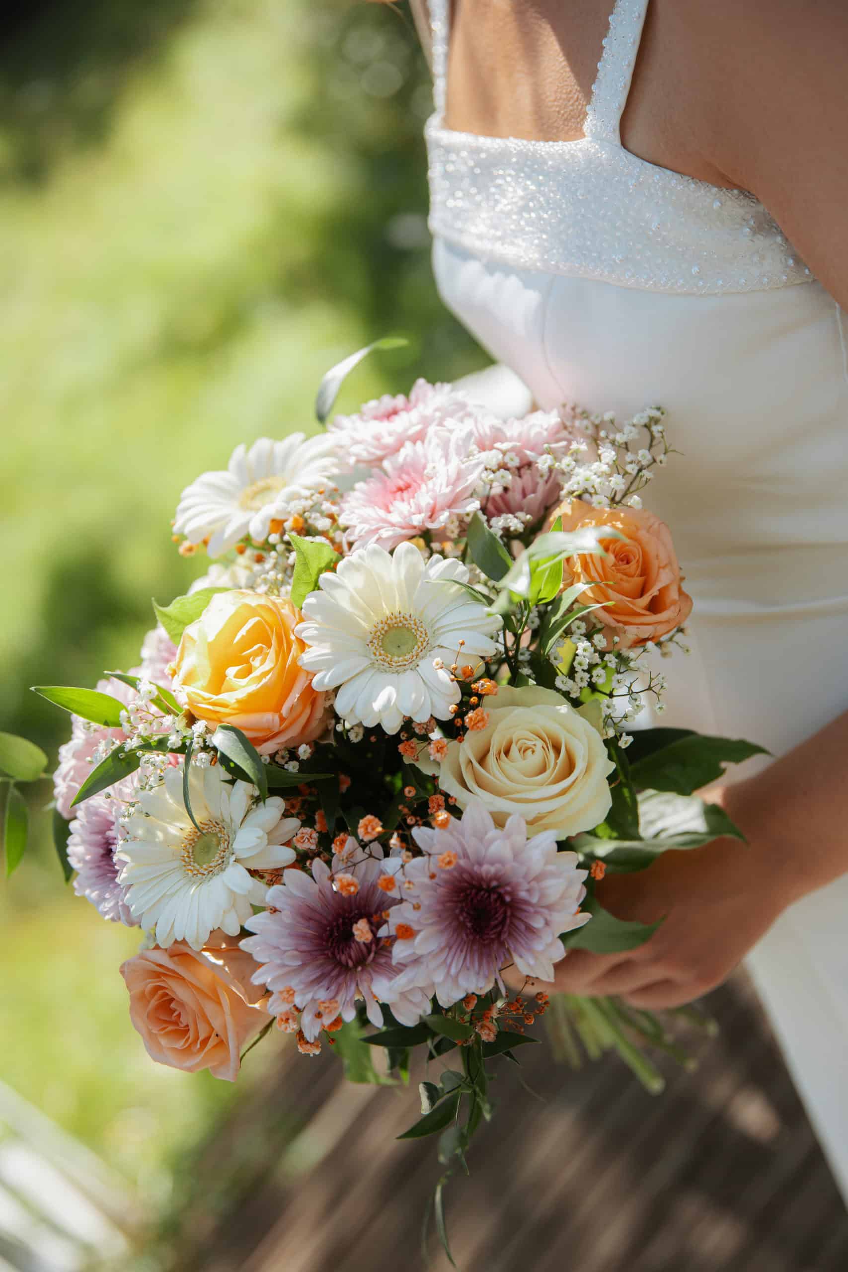 Nærbilde av en vakker bryllupsbukett med roser, daisies og andre blomster.