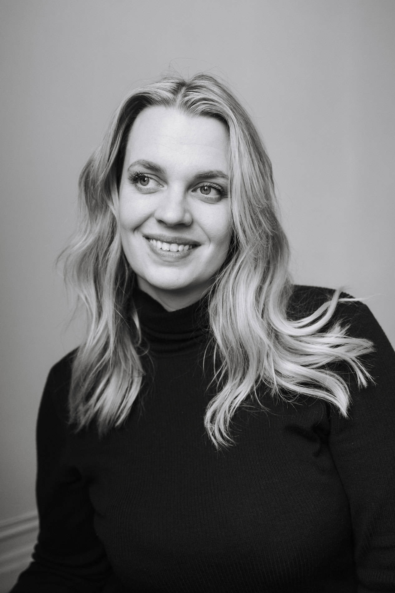 Heidi Henriksen smiler i svart-hvitt portrett, viser sin kreative og profesjonelle side.