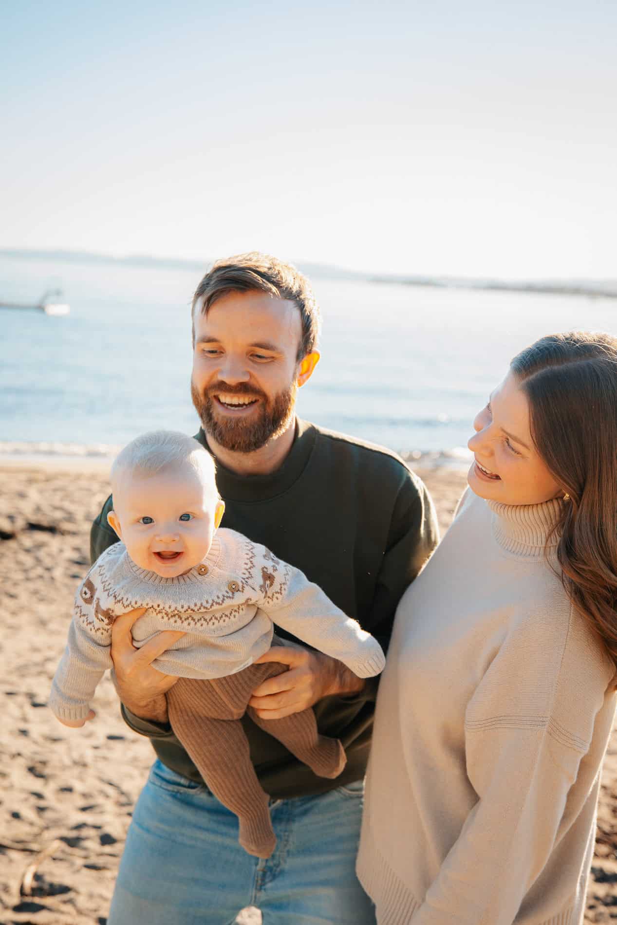 Familiefotografi med smilende familie på stranden i Oslo, perfekt for familiebilder og minner.