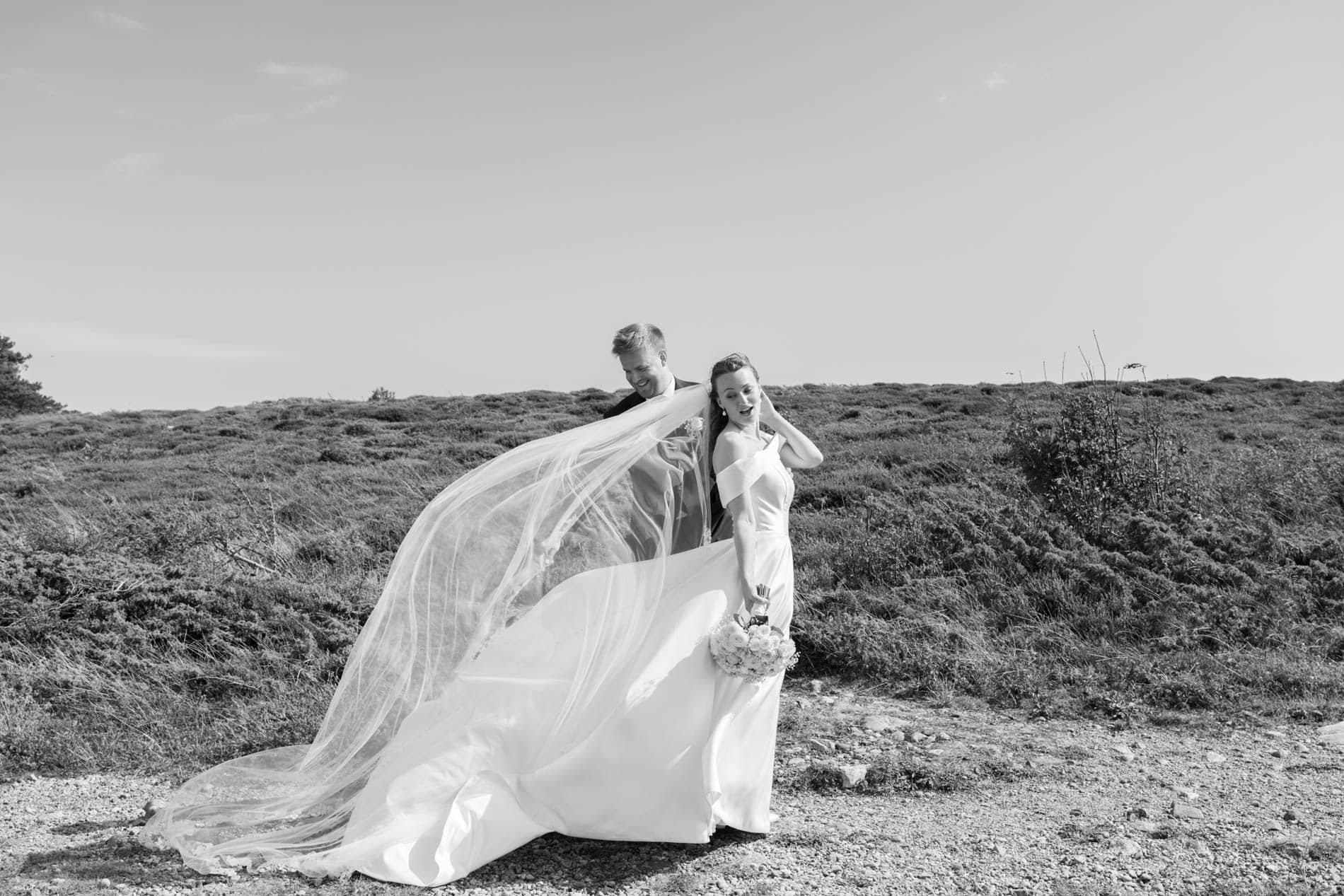 Bryllupsfoto av brudepar med kjole og dress i utendørs landskap.