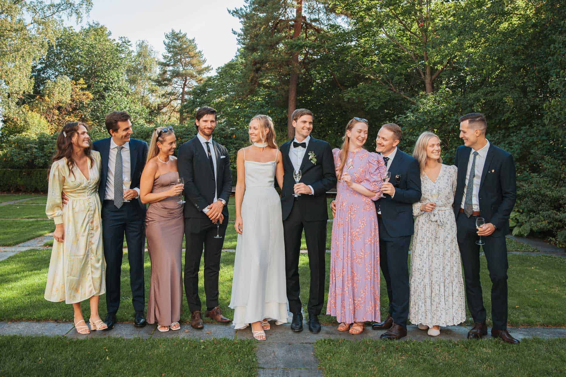 Gruppe av brude- og bryllupsgjester i en park i Oslo, feirer kjærlighet.